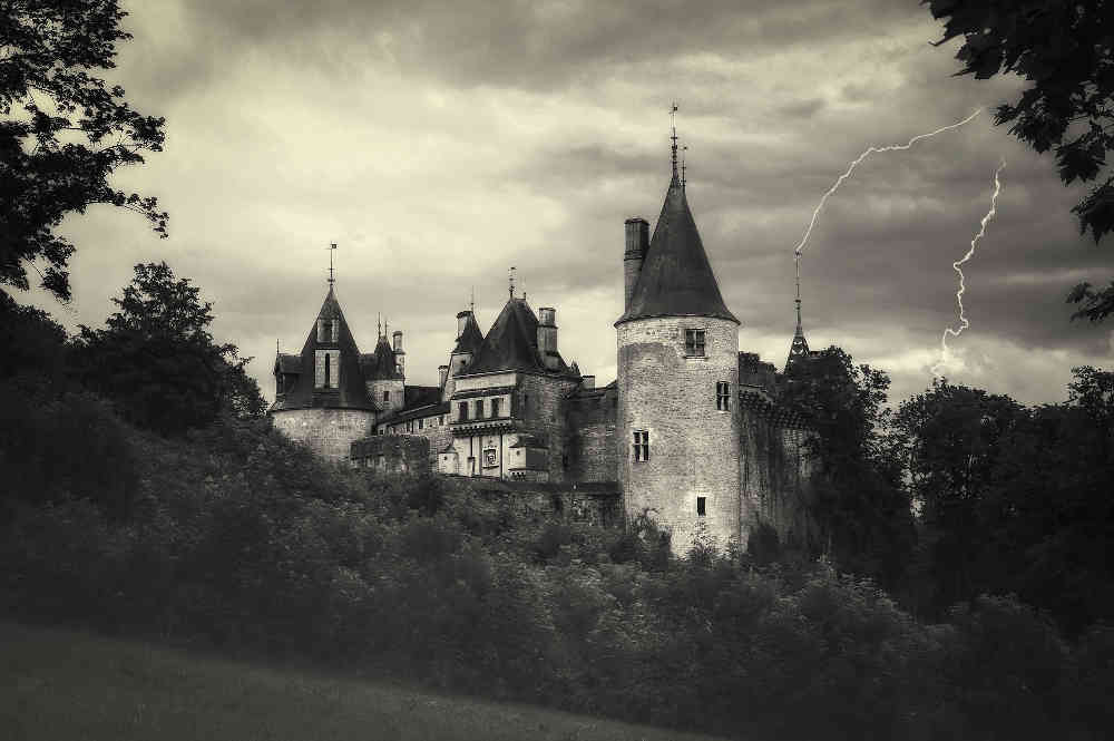 Castle with conical-roofed turrets - receiving two lightening strikes to the turret-spikes.  Greyscale.